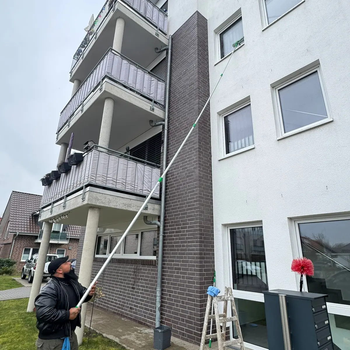 Jonas Gebäudereinigung reinigt die Fassade eines mehrgeschossigen Objekts mit einer Teleskopstange