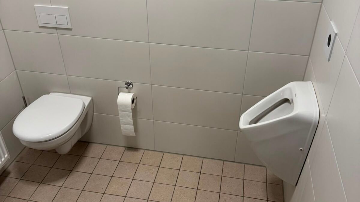 Sauber, aber Seife leer? Sanitärprobleme richtig auseinanderhalten 6 Sauberer Sanitärraum mit Toilette, Urinal und Bodenablauf