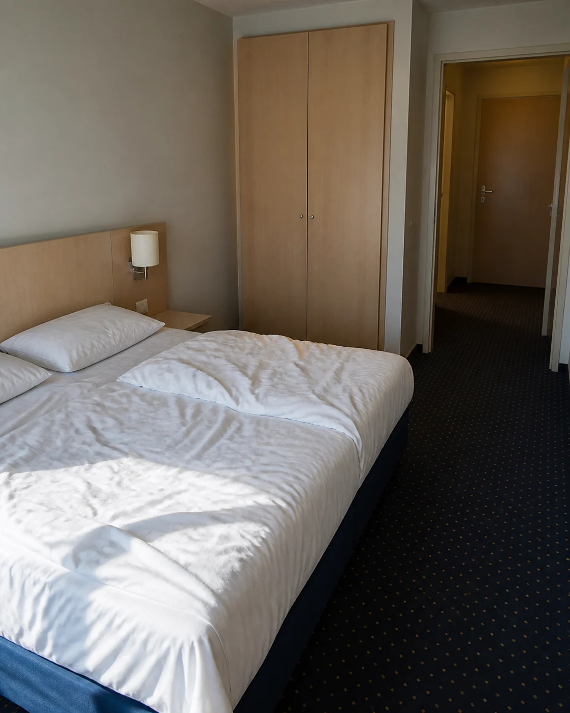 Bettwäsche nur auf ausdrückliche Bitte abziehen Hotelbett mit zerknitterter Bettwäsche in einem leeren Zimmer