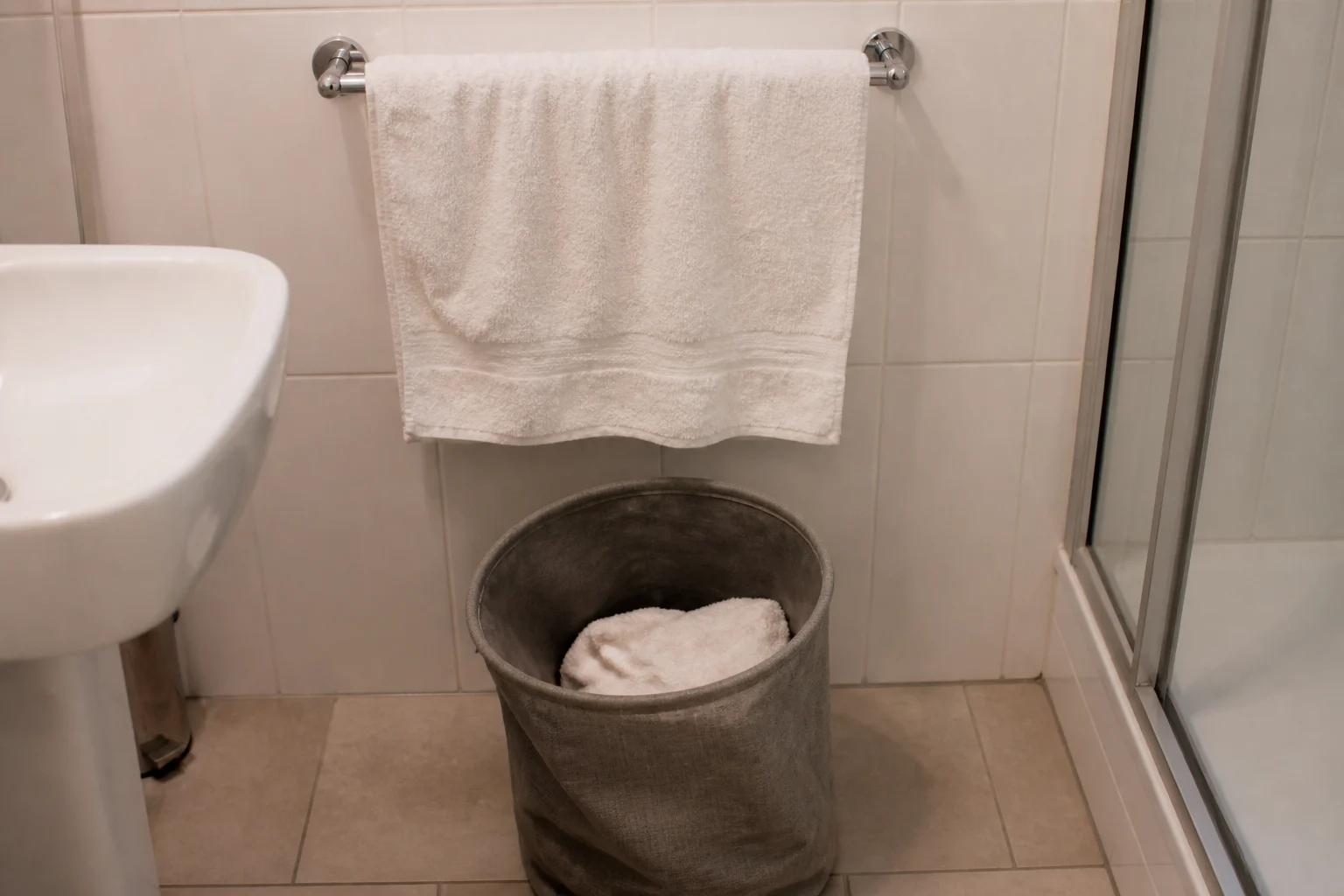 Handtuchsignal nur am vorgesehenen Sammelort Ein Handtuch hängt auf einer Stange, ein weiteres liegt in einem Stoffkorb im Hotelbad