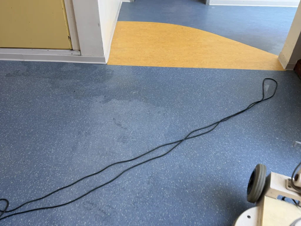 Anschlusskabel einer Reinigungsmaschine liegt vor dem Start im Laufbereich